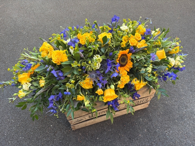 Blue and yellow funeral spray